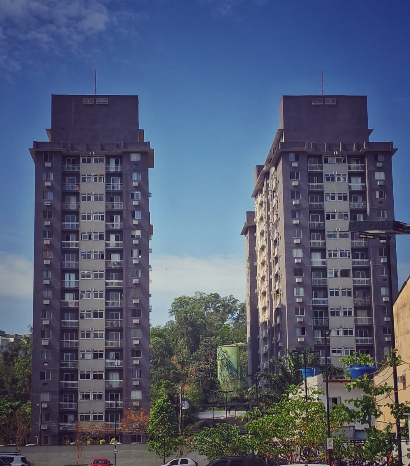 Fachada das duas torres do Condomínio Village Vip, vistas de baixo contra o céu azul